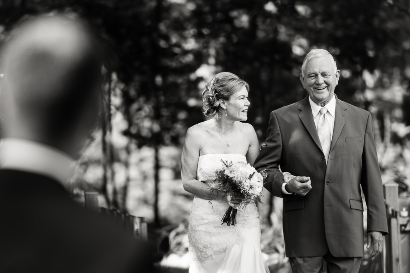 Documentary wedding photography of bride walking down aisle with father.