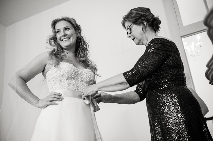 Mother of the bride ties a bow on the wedding dress in a New Orleans wedding.