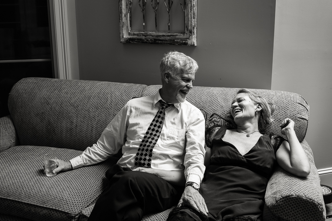 Middle aged couple relaxing on couch during wedding reception.