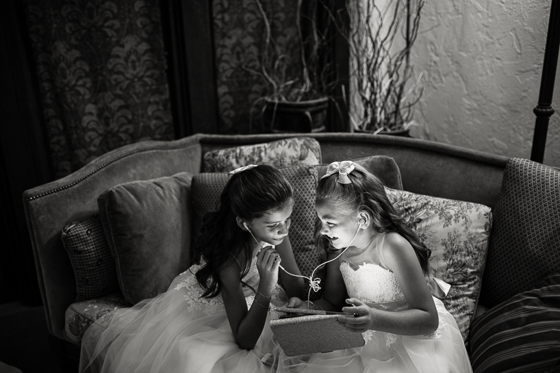 Denver wedding photojournalist at The Villa Parker captures flower girls sharing iPad before the ceremony.