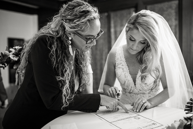 Picture of an officiant and bride signing a marriage license after a ceremony.