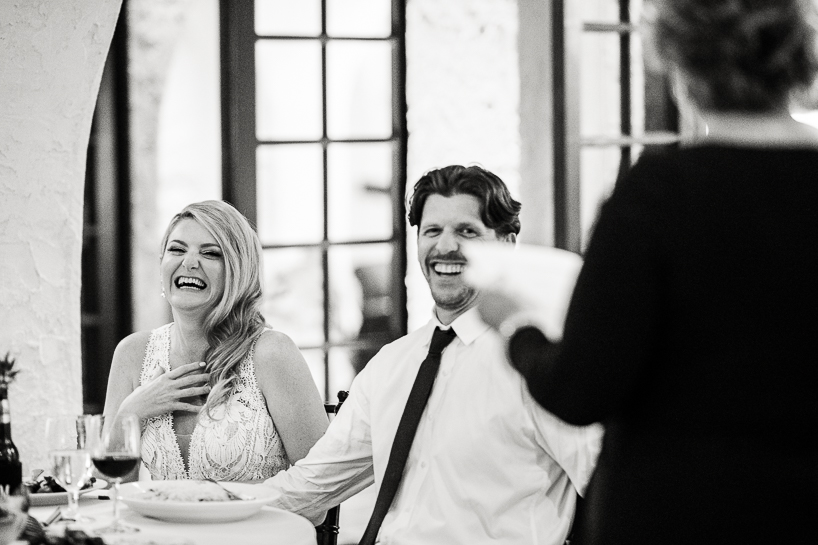 A bride and groom laughing at a toast given by the mother of the bride at a Villa Parker wedding by Denver wedding photojournalist.