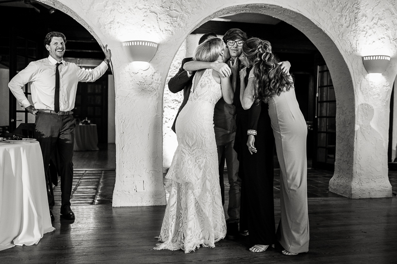 A teenage boy at a wedding reception is embarrassed by five women embracing and kissing him.
