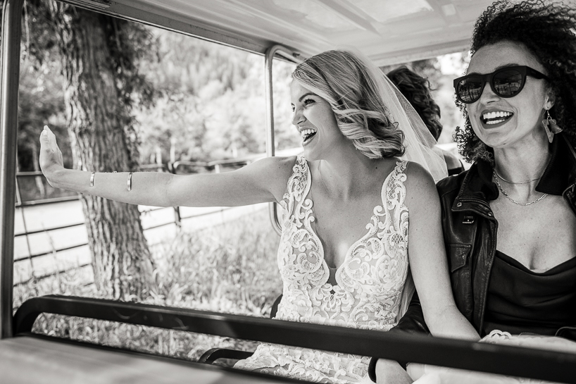 Joy before a wedding as bride and friend share a golf cart.