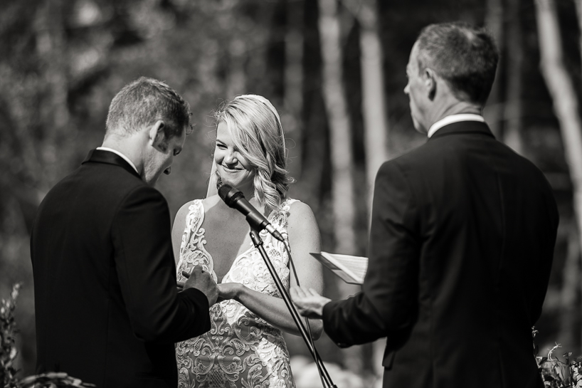 Groom places ring on bride's finger during Aspen wedding ceremony.
