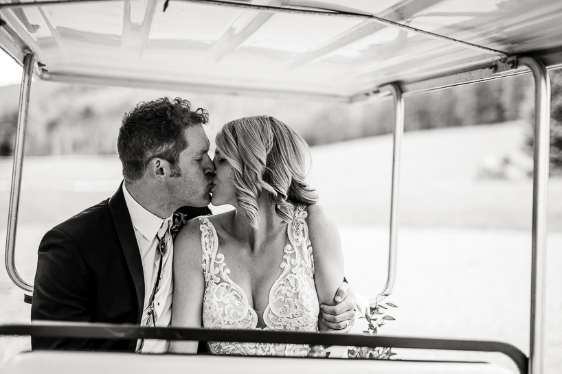 Bride and groom kiss in golf cart after a wedding in Aspen, Colorado.