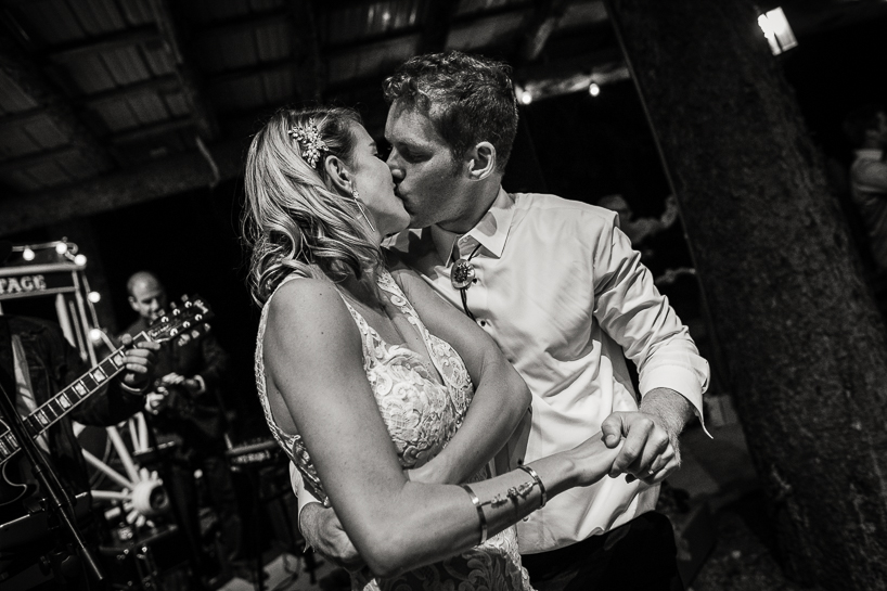 Wedding couple kiss at rustic outdoor wedding reception in Aspen.