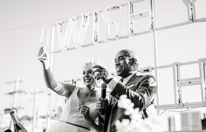 Bride and groom toast their guests at a rooftop wedding reception at The Ramble Hotel in Denver.