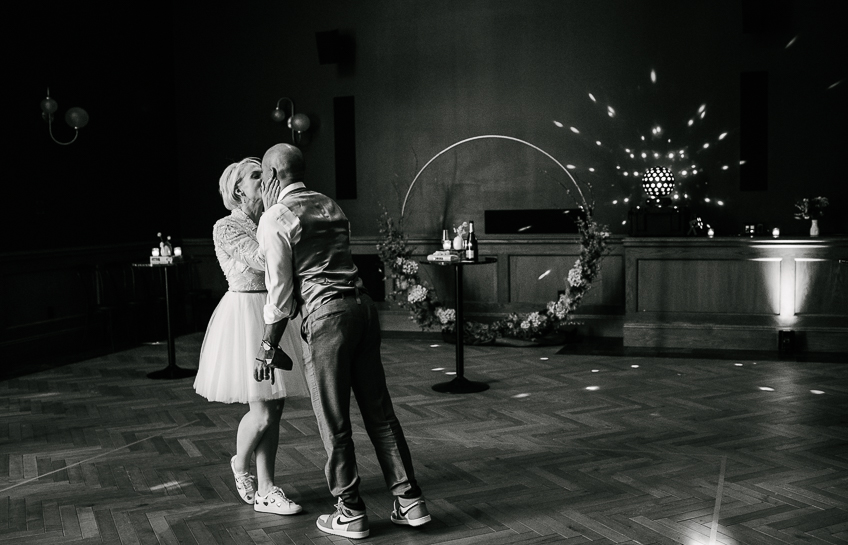 Bride and groom wearing sneakers kiss on the dance floor in Denver's Vauxhall.