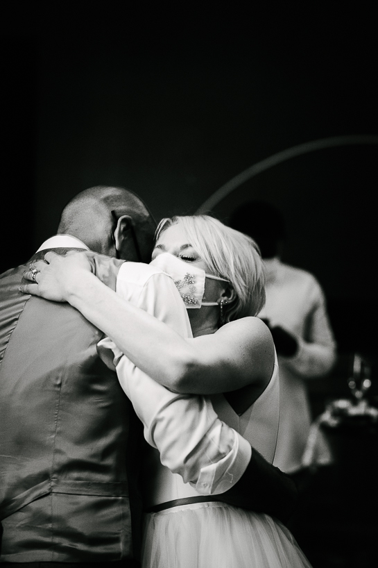 Groom and bride wearing Covid masks embrace on the dance floor of The Ramble Hotel in Denver.