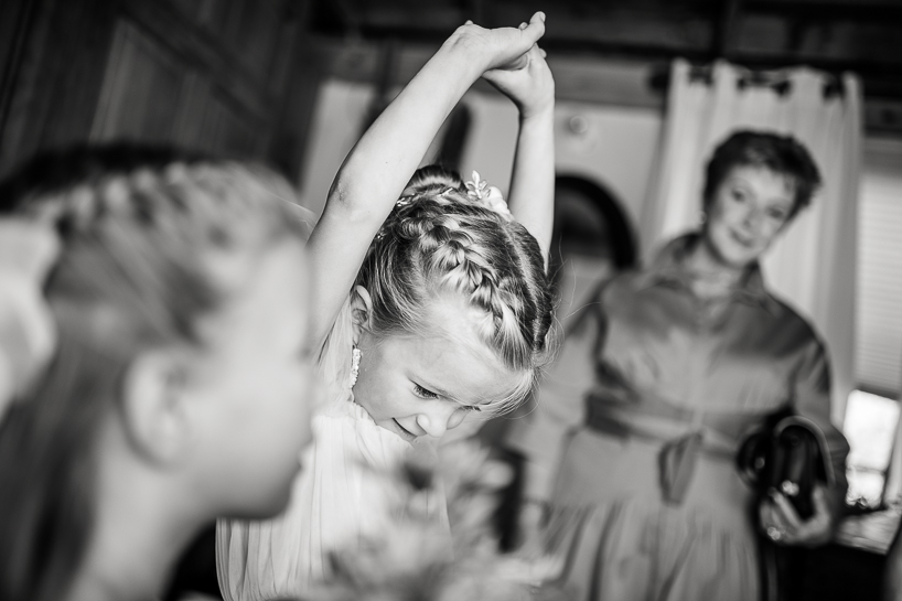 Flower girl stretches during preparations at Black Cat Farm in image by Denver wedding photographer.