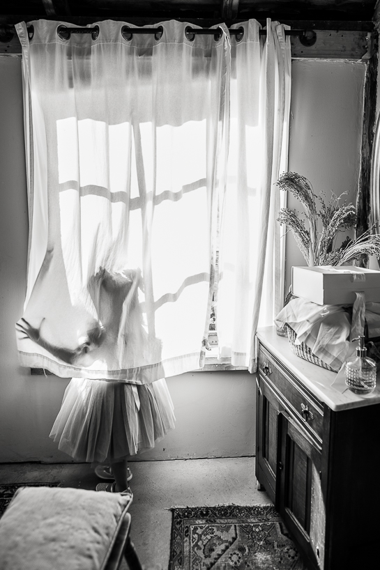 Flower girl plays in curtain, forming a silhouette before the ceremony, as shown by Denver wedding photographer who also likes to play with light and shadow.