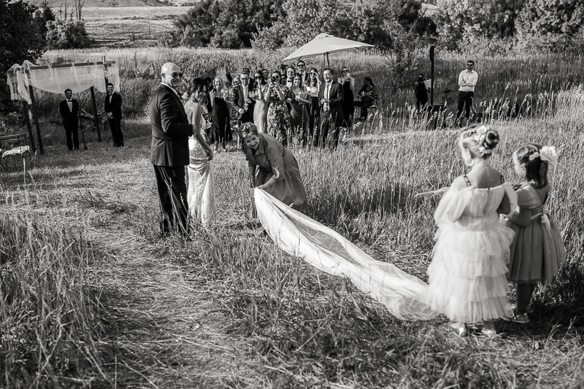 Flower girls step on bride's veil, pulling it off in picture by Denver wedding photographer