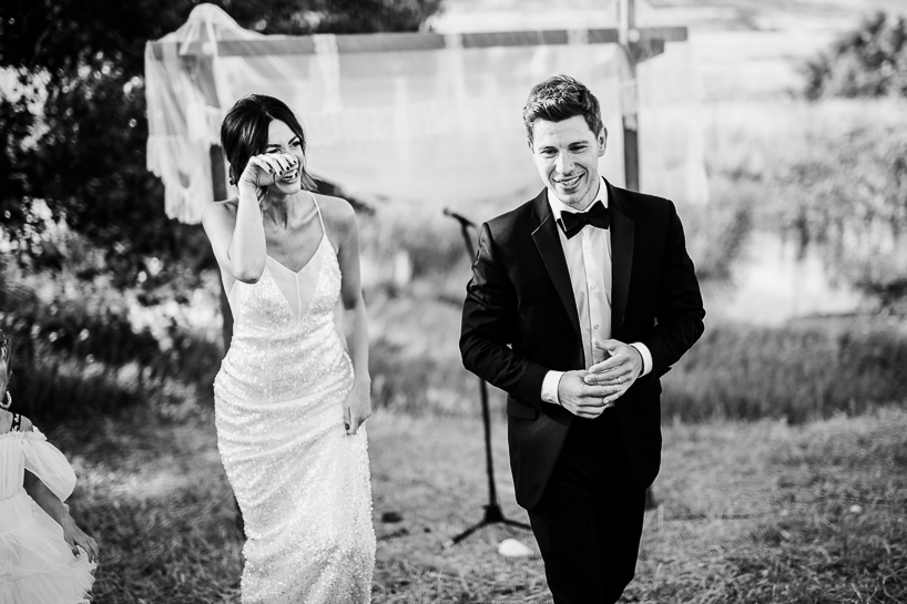 Bride and groom leave wedding ceremony, bride wiping away a tear and groom playing with his ring in country ritual by Denver wedding photographer.