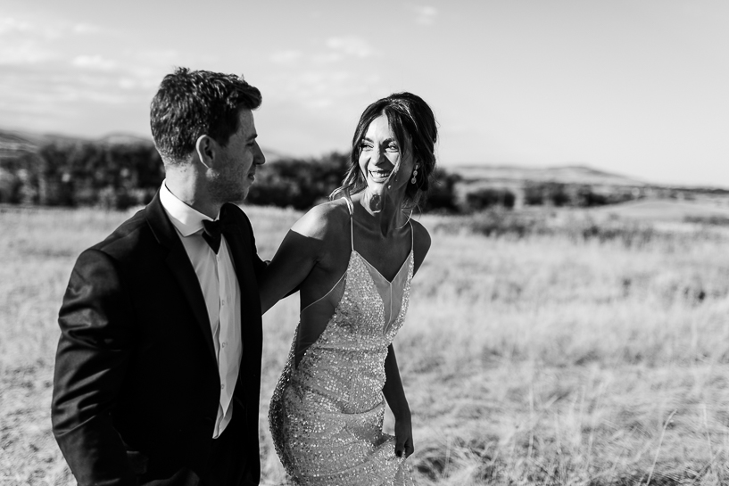 Photograph by Denver wedding photographer of bride and groom leaving ceremony site in an open field.