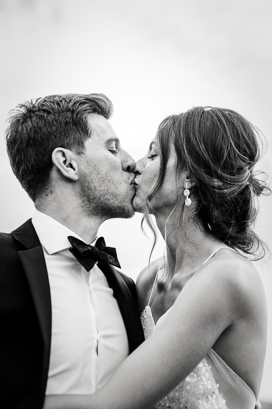 Couple kisses at outdoor reception as captured by Denver wedding photographer.