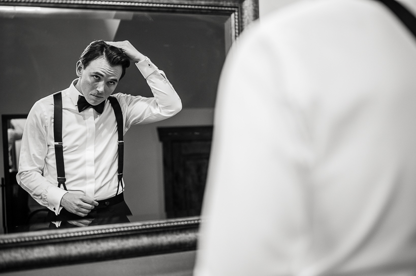 Groom presses on hair before wedding to reflect that Denver wedding photographer covers both sides of preparations.