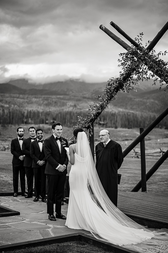An establishing image of an outdoor ceremony on the Devil's Thumb Ranch wedding deck. There is a storm brewing in the distance.