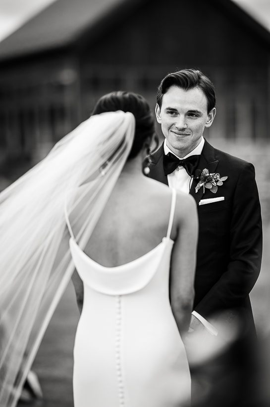 Image of a groom exchanging vows with his bride in an outdoor wedding ceremony as seen from her perspective.