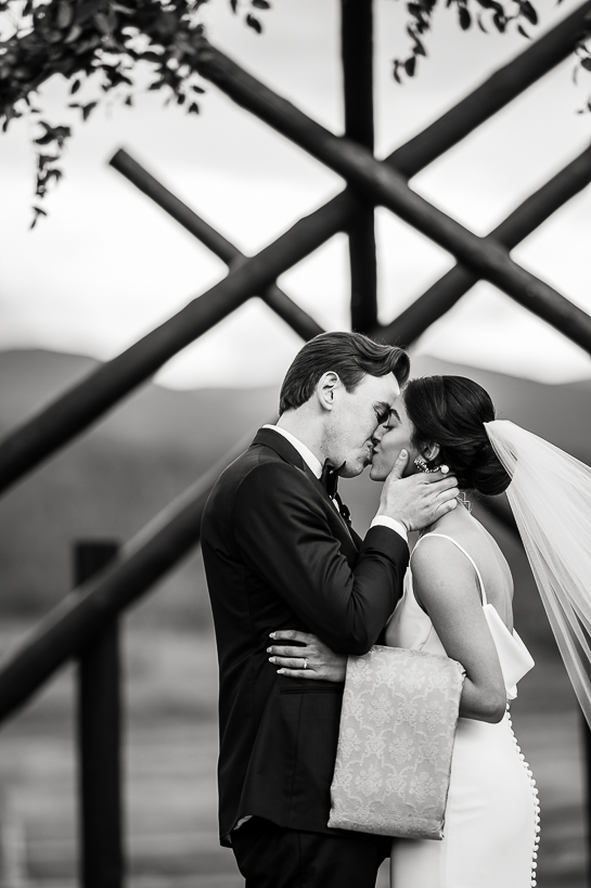 Black and white wedding photo of couple kissing at conclusion of a Colorado mountain wedding ceremony.