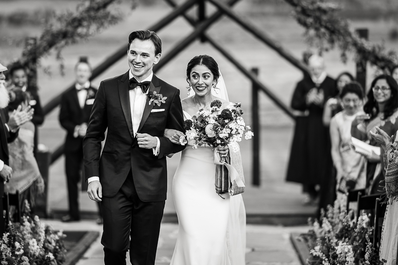 Bride and groom exit the Devil's Thumb Ranch wedding deck in a black and white photo.