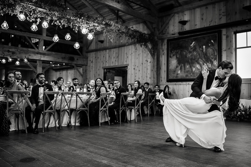 Groom dips bride at the conclusion of their first dance in a barn-like reception venue in Winter Park, Colorado.